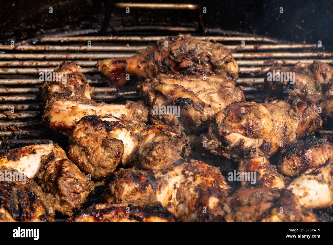 Gegrilltes traditionelles jamaikanisches würziges Jerkchhuhnchen mit über Holzkohleffeuer. Stockfoto