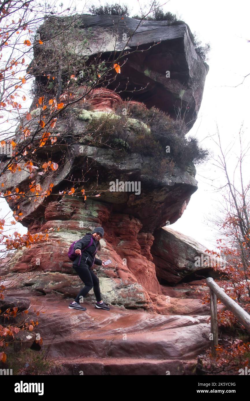 Hinterweidenthal, Deutschland - 1. Januar 2021: Frau am Fuße des Teufelstisches im Pfälzer Wald an einem kalten, bewölkten Wintertag. Stockfoto