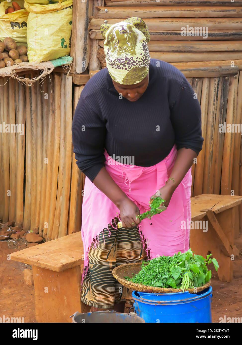 Frau auf dem Dorflebensmittelmarkt Rasieren von Gemüsegrünen zum Verkauf Stockfoto