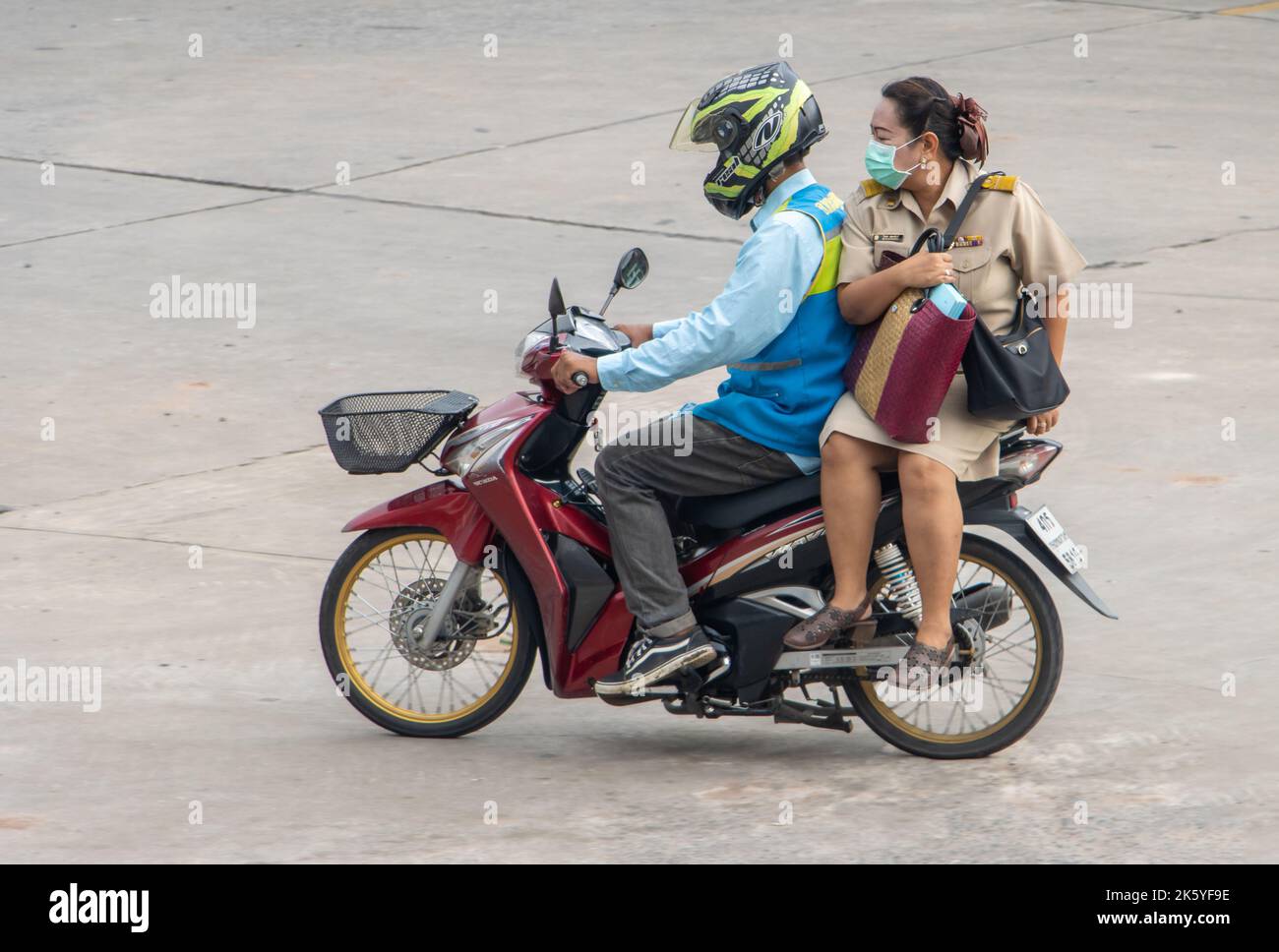 SAMUT PRAKAN, THAILAND, Okt 03 2022, Ein Taxifahrer auf einem Motorrad fährt mit einer Frau in der Uniform eines Beamten. Stockfoto