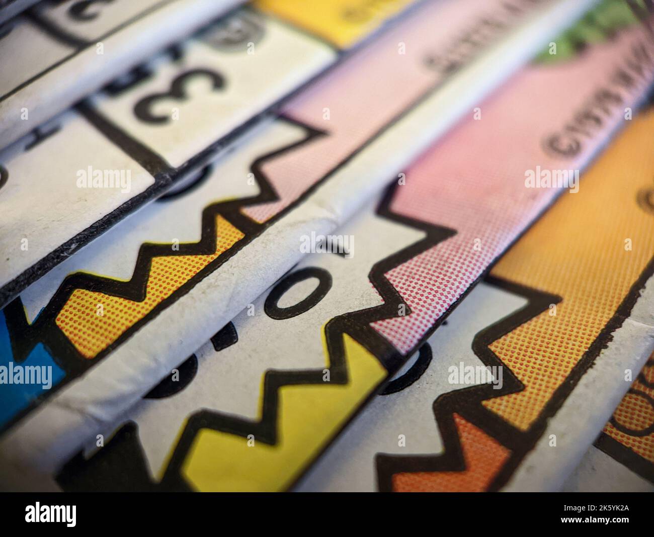 Die Nahaufnahme einer alten Comicsammlung, die auf einem Stapel gestapelt ist, erzeugt eine bunte Papierstruktur mit abstrakten Formen im Hintergrund Stockfoto