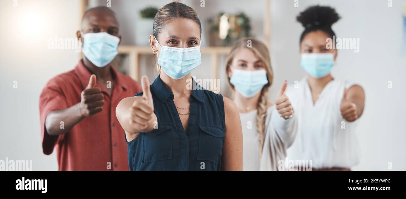 Daumen hoch, die covid Pandemie und Mitarbeiter mit Maske im Geschäft zeigen eine positive Einstellung am Arbeitsplatz. Coronavirus-Epidemie, Gesundheit und Sicherheit der Mitarbeiter Stockfoto