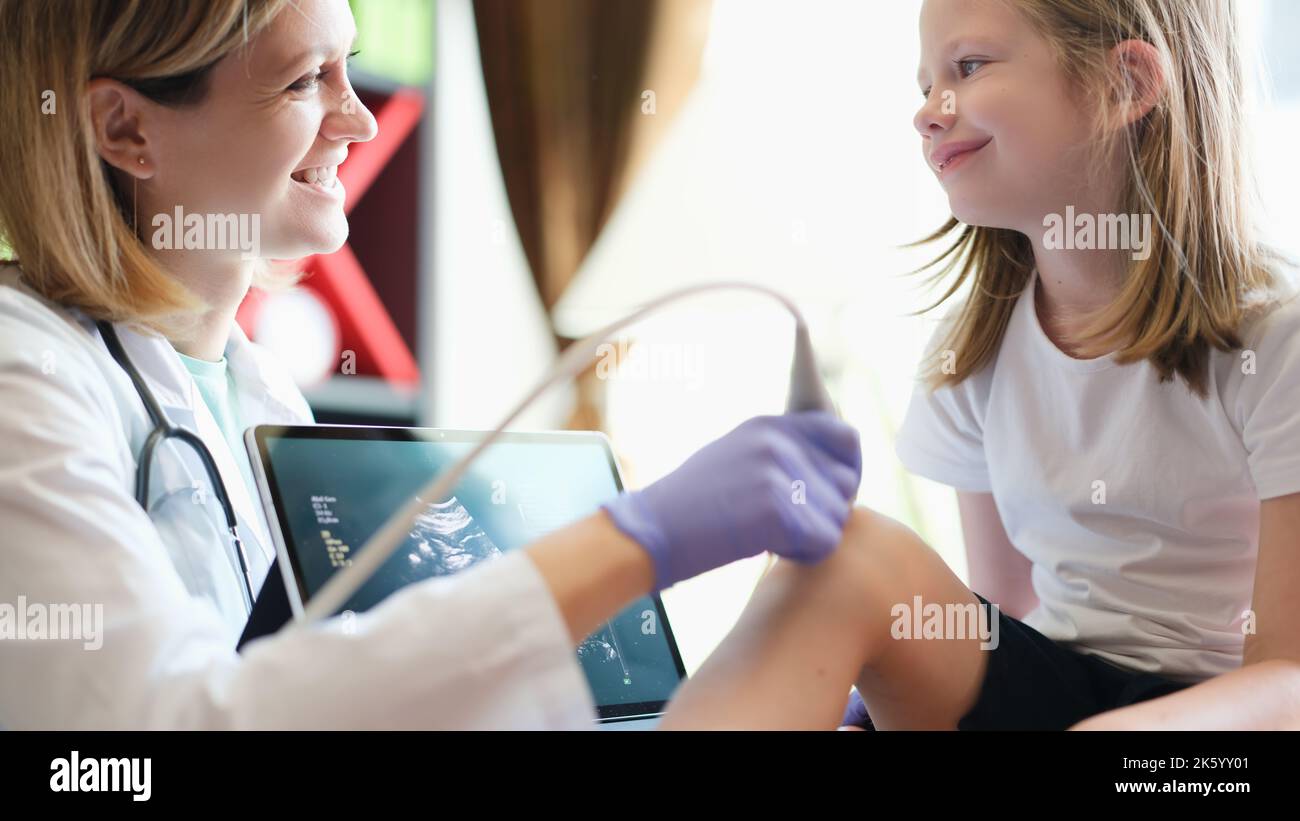Ärztin, die Ultraschalldiagnostik des Kniegelenkes des Kindes macht Stockfoto