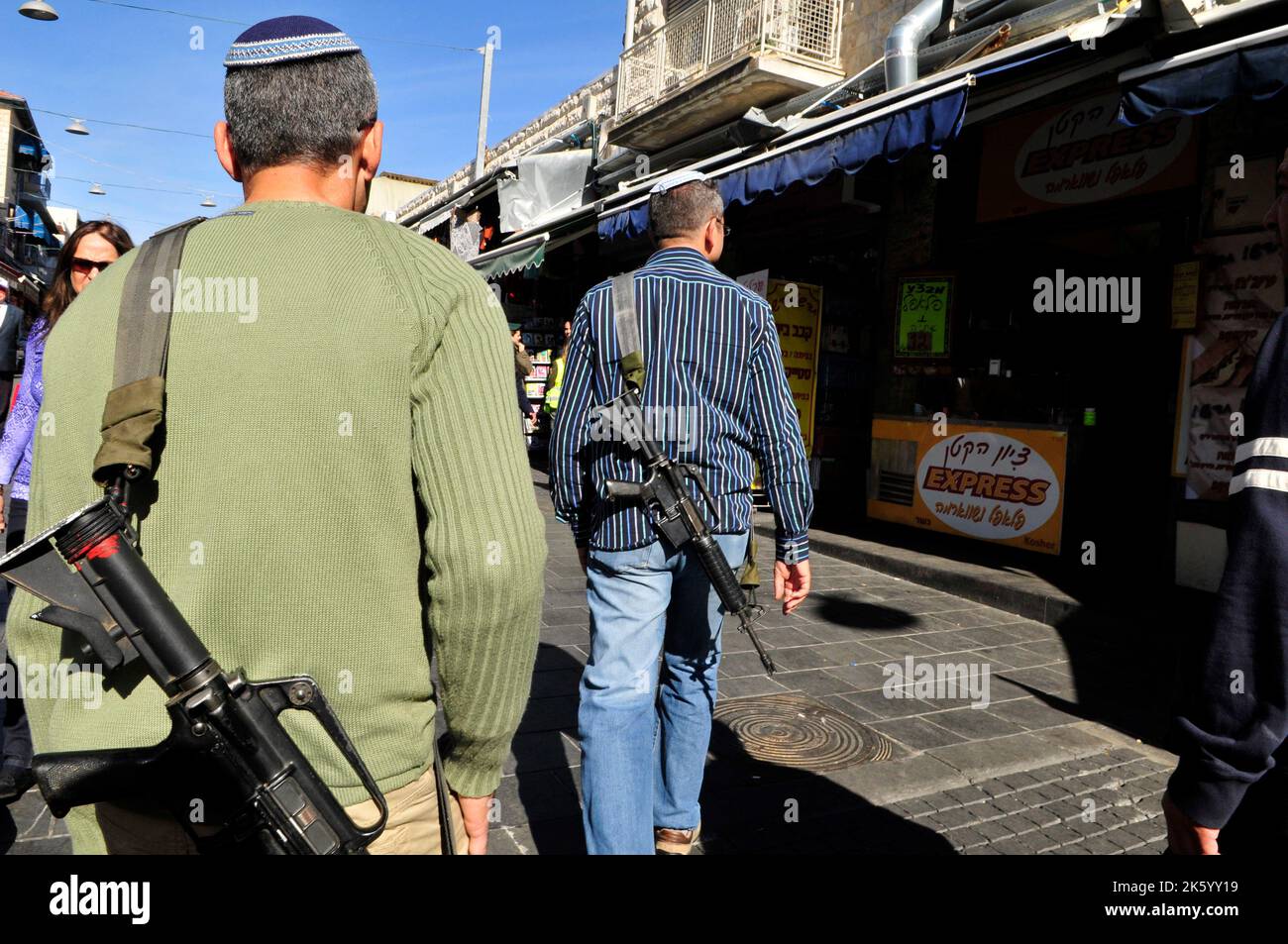 Jüdische Siedler mit ihren Gewehren auf dem lebhaften Machane Yehuda Markt in Jerusalem, Israel. Stockfoto