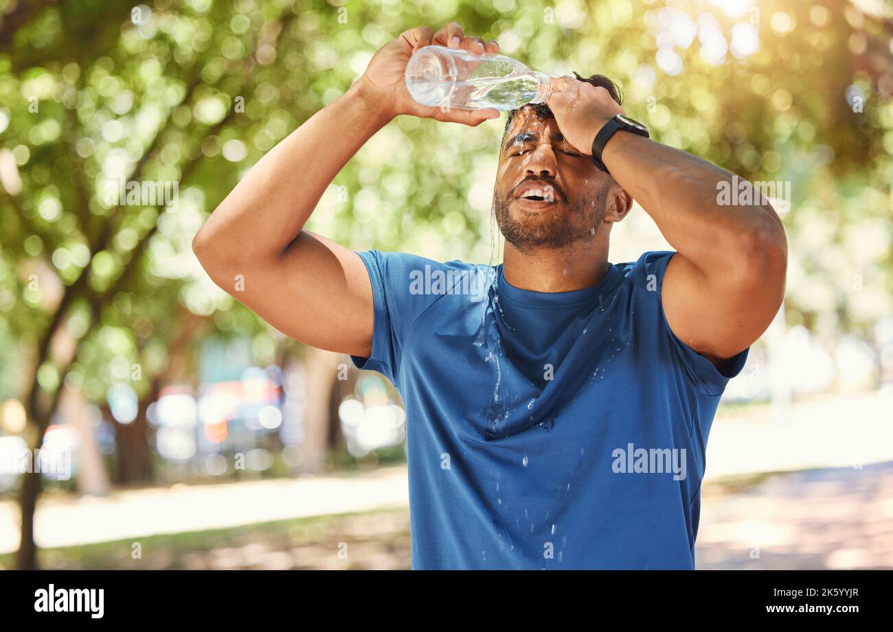 Junger, gemischter Athlet, der seinen Kopf mit Wasser bespritzt und hydratisiert bleibt, während er sich auf Gesundheit und Fitness konzentriert. Durstiger Mann, der eine Pause von nimmt Stockfoto