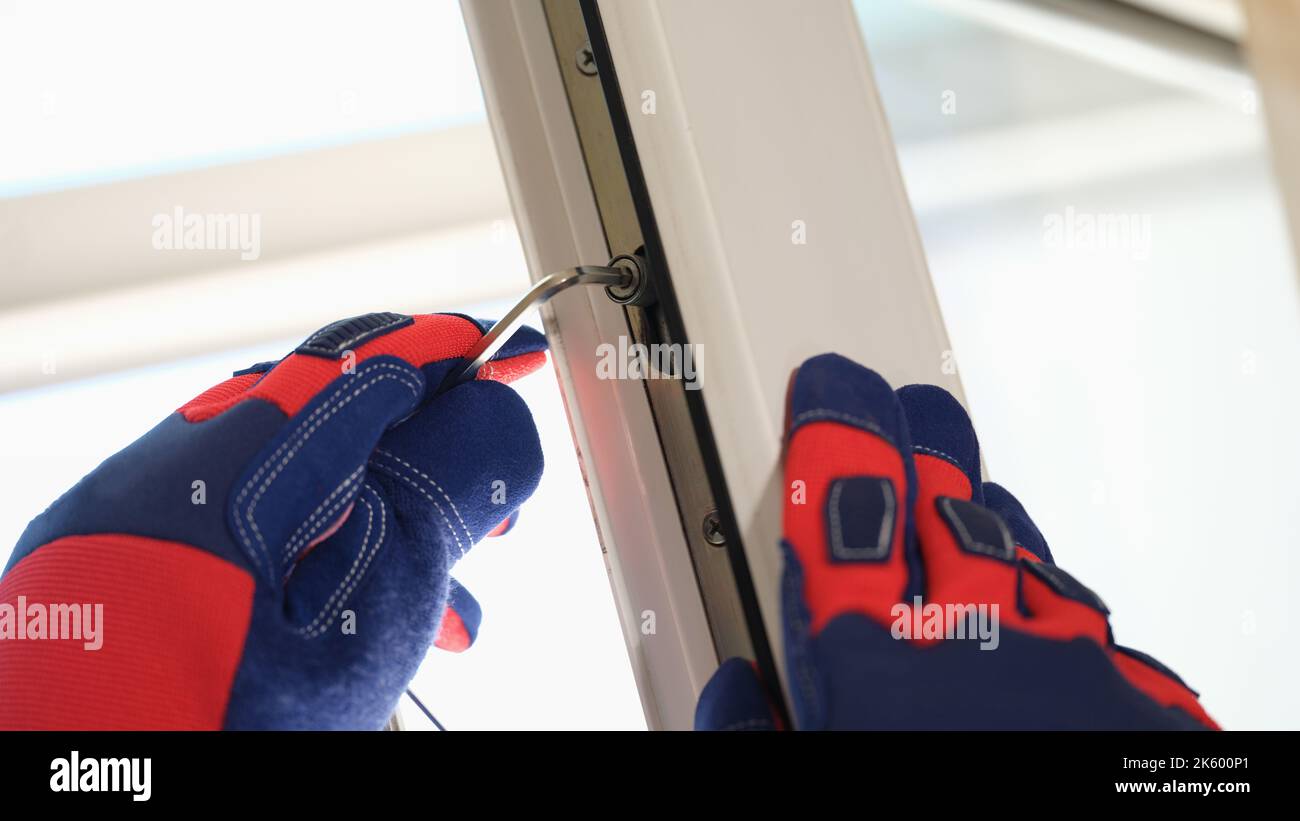 Die Hände der Arbeiter passen die Schlösser der offenen pvc-Fenster mit einem speziellen Schlüssel an Stockfoto