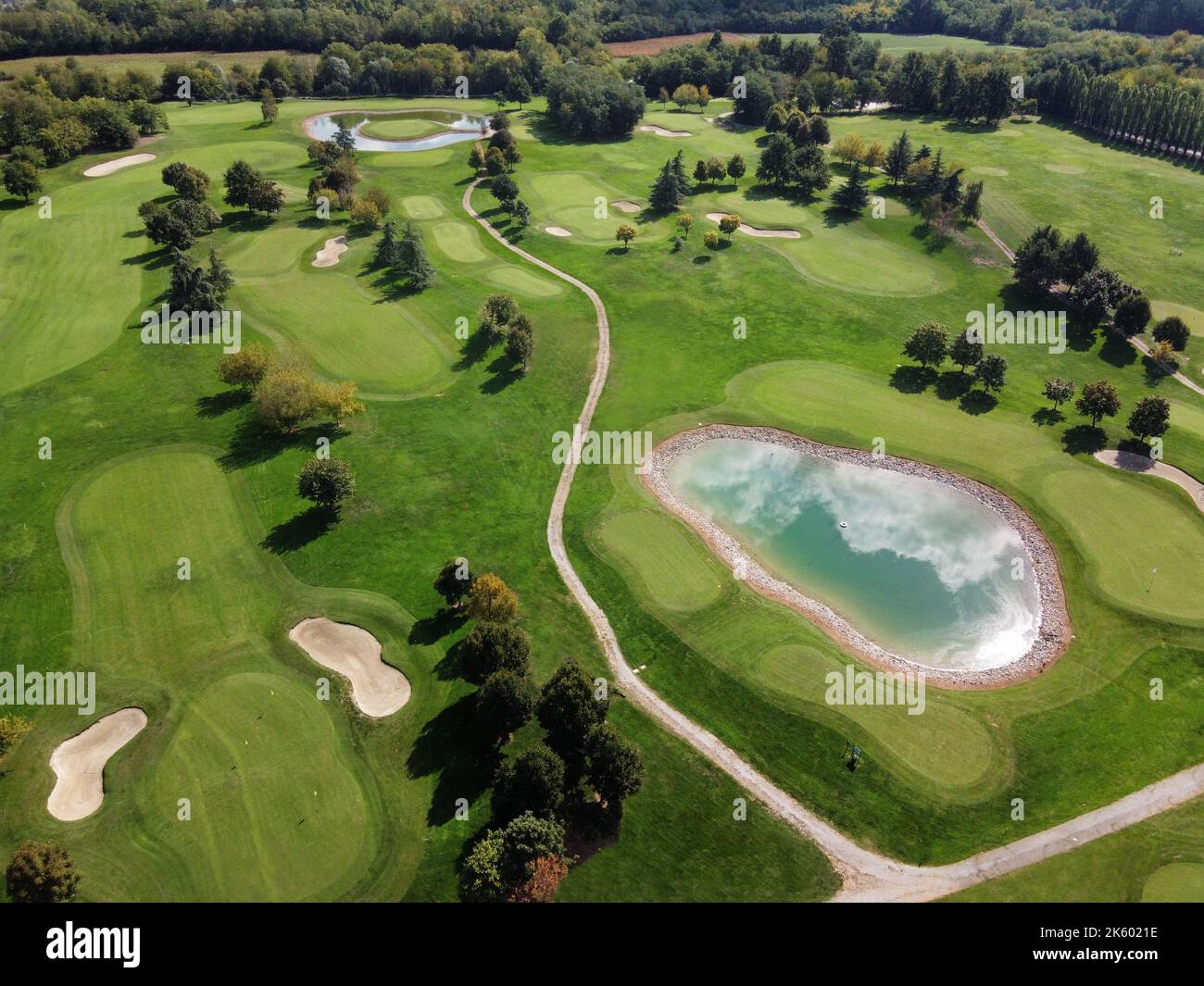 Luftbild grüne Landschaft von üppigen Golfplatz mit Straßen und kleinen Teich unter gepflegten Bäumen Stockfoto