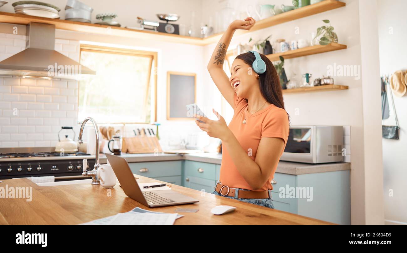 Junge schöne fröhliche gemischte Rennen Geschäftsfrau hält und mit einem Telefon, während Kopfhörer und Musik von zu Hause aus zu hören. Eins Stockfoto
