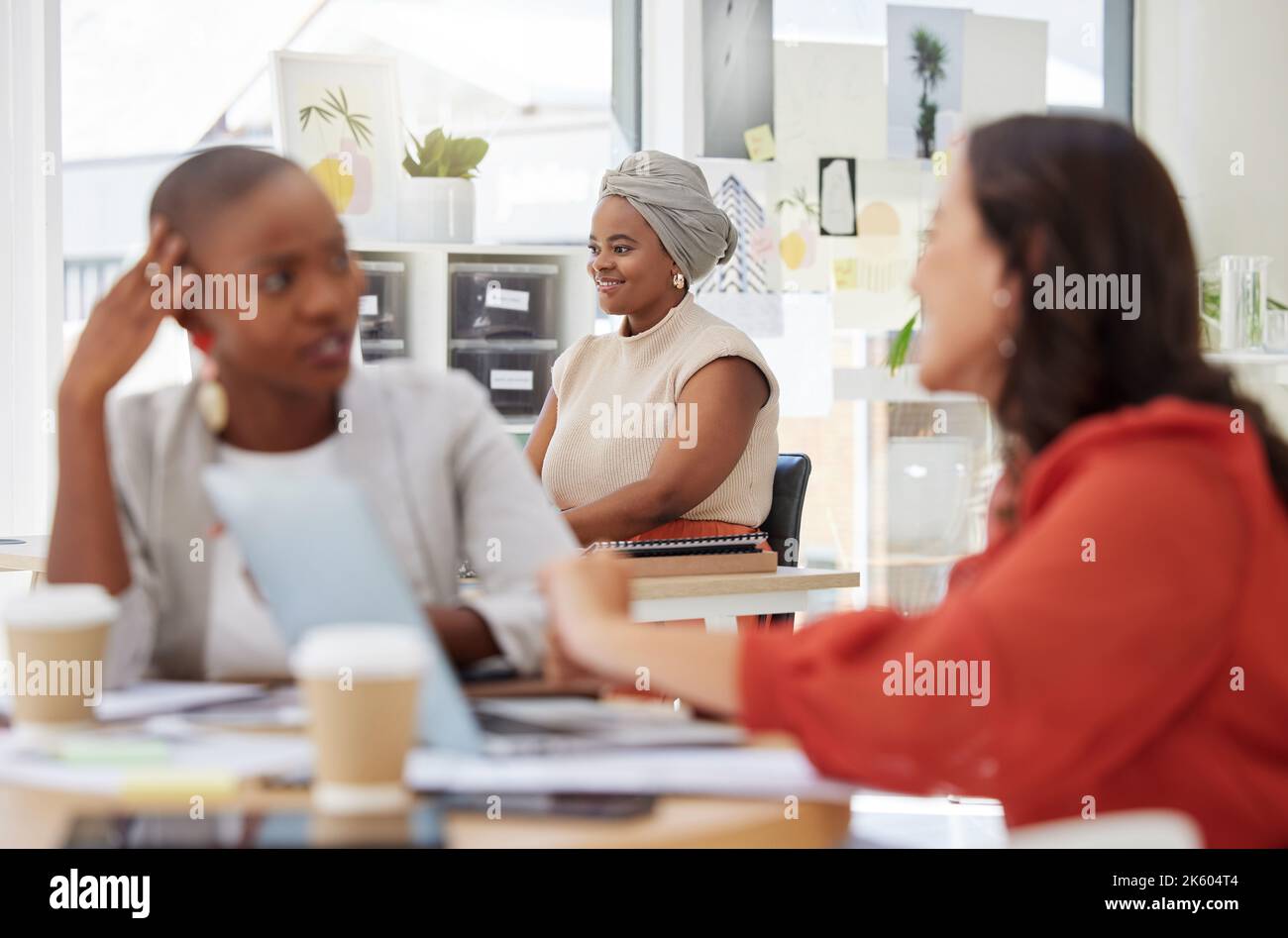 Lächelnde, ehrgeizige afroamerikanische Geschäftsfrau, die im Büro sitzt und arbeitet. Selbstbewusster, fokussierter ethnischer Profi, der hinter dem Team sitzt Stockfoto