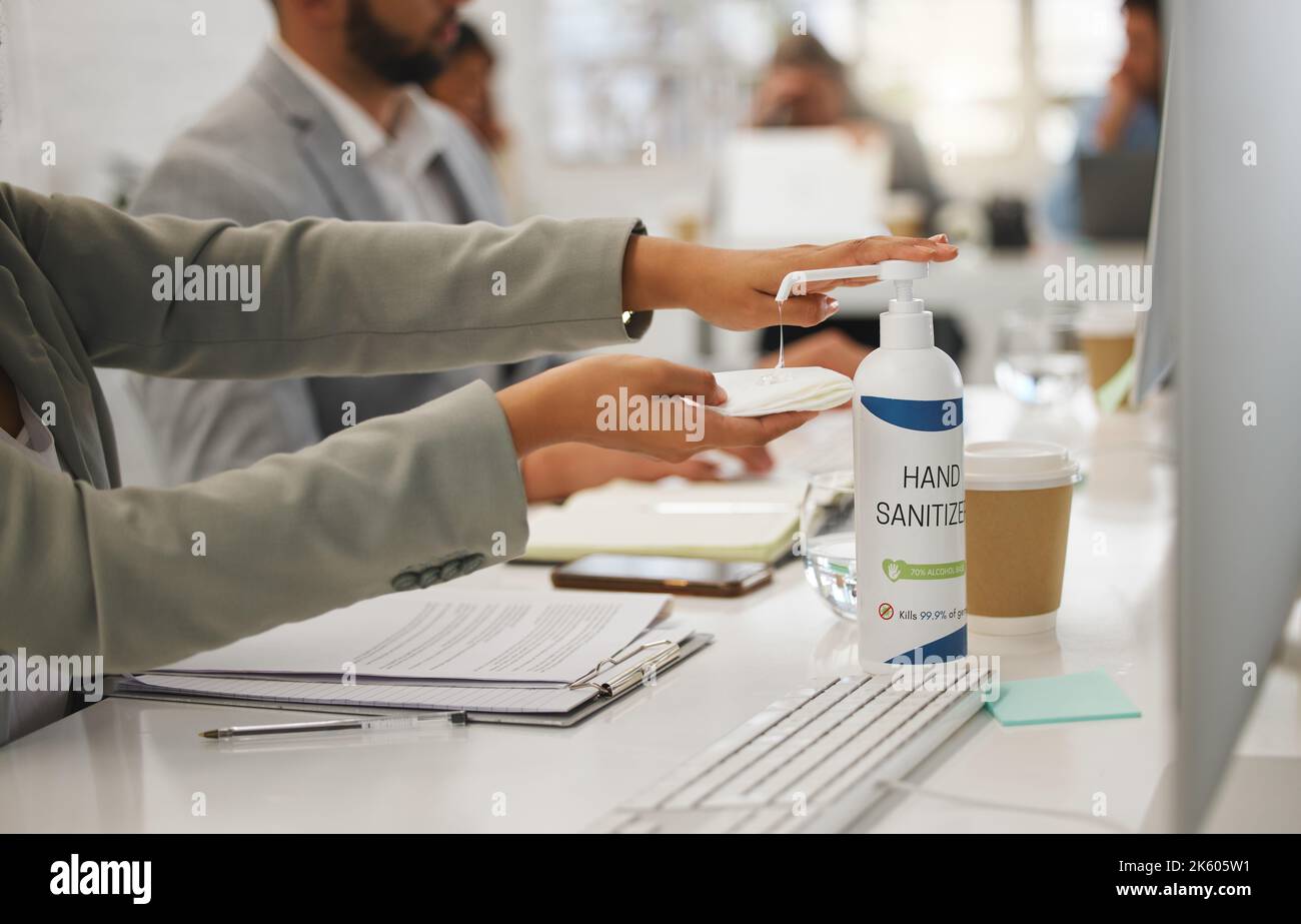 Geschäftsleute, die ein Gewebe halten und ein Handdesinfektionsmittel aus einer Flasche verwenden, während sie in einem Büro arbeiten. Professionelle Mitarbeiter, die Desinfektionsmittel zum Schutz verwenden Stockfoto