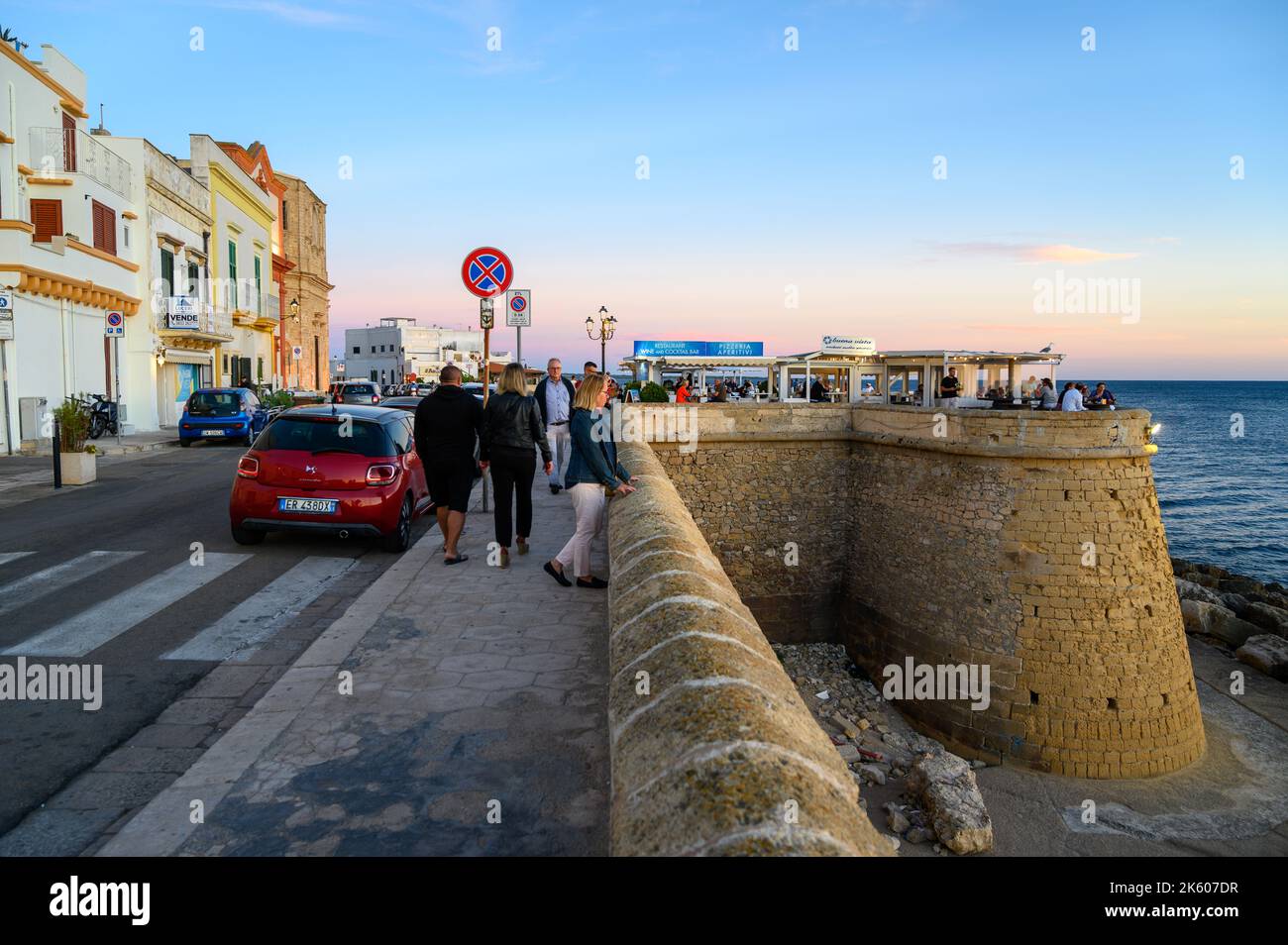 Menschen, die Speisen und Getränke im Freiluftrestaurant Buena Vista am mittelalterlichen Stadtwall am Meer in der Altstadt von Gallipoli, Apulien (Apulien), Italien, genießen. Stockfoto