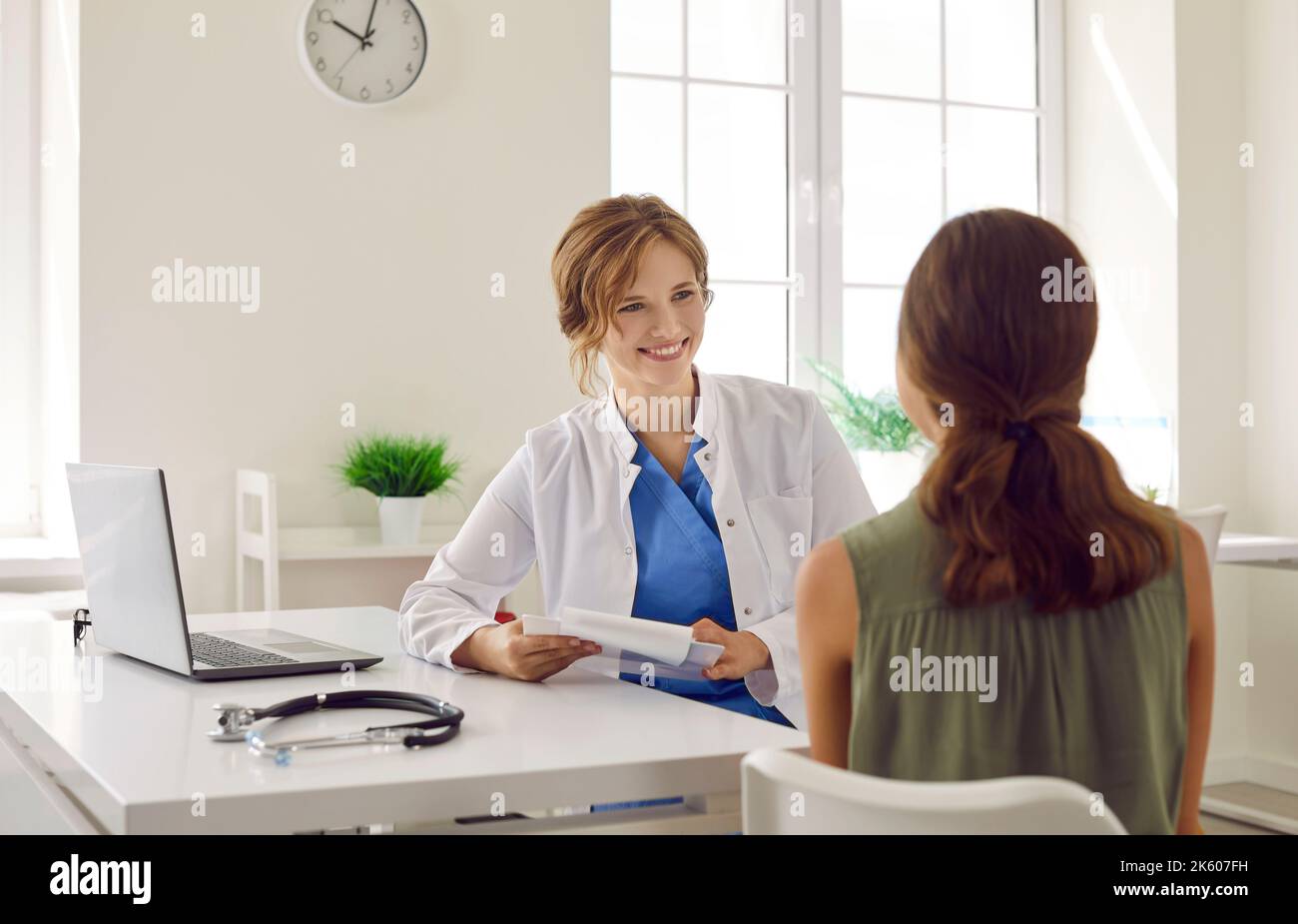 Freundliche Ärztin, die an ihrem Tisch sitzt und einem Kind eine medizinische Beratung gibt Stockfoto