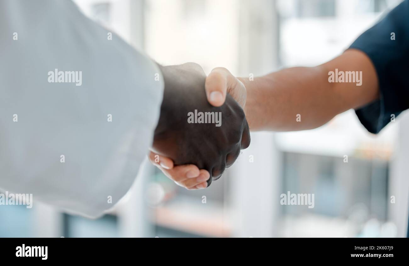 Zwei Ärzte schütteln sich die Hände, während sie in einem Krankenhaus zusammenarbeiten. Medizinische Fachkräfte begrüßen sich gegenseitig bei der Arbeit in einer Klinik. Kollegen Stockfoto