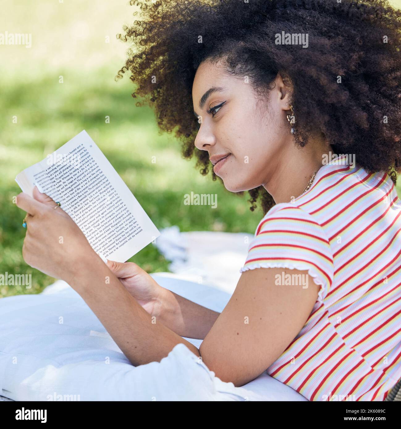 Schwarze Frau liest Buch, entspannen Sie sich im Park und Picknickdecke mit Roman in der Natur. Bildung, Lernen und weibliche Studentin in Brasilien in College oder Stockfoto