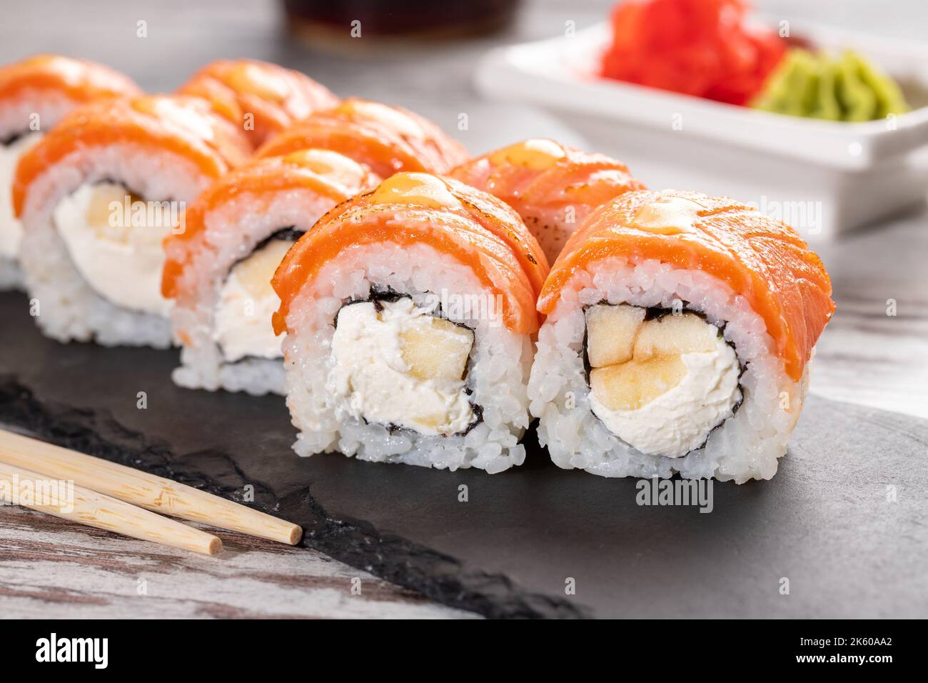 Beliebtes Essen. Set von Philadelphia Sushi auf schwarzem Betonplatte auf dem Tisch. Nahaufnahme von Sushi-Brötchen mit Lachs und Käse und Aal Stockfoto