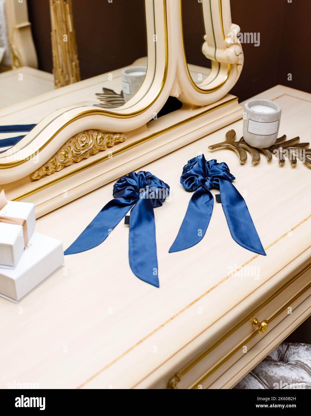 Haarbinder aus Seidenstoff für echte elegante Damen. Exquisite Frauen handgefertigten blauen Scrunchy liegen auf dem Tisch zwischen luxuriösen Interieur Details. HaarZugang Stockfoto