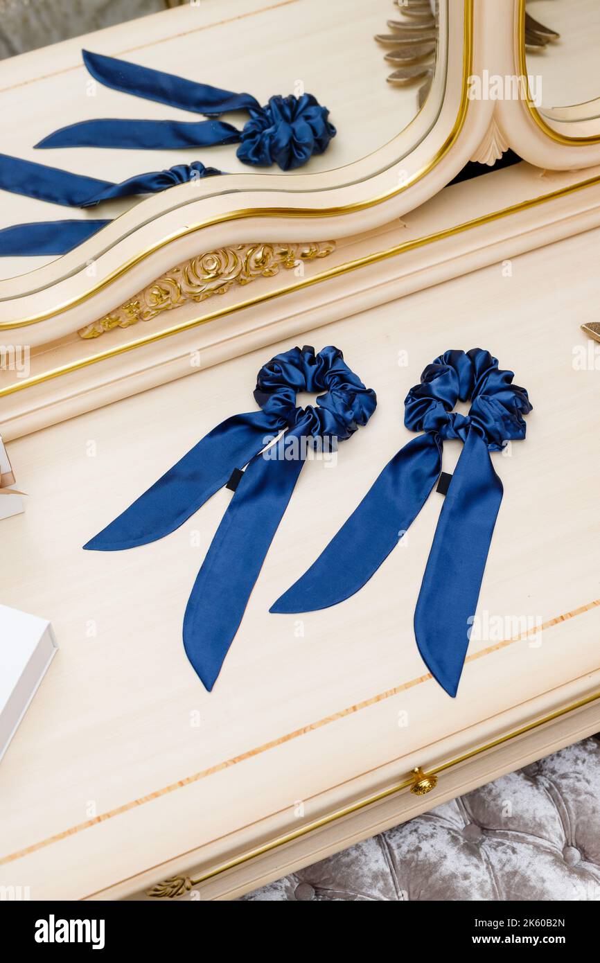 Haarbinder aus Seidenstoff für echte elegante Damen. Exquisite Frauen handgefertigten blauen Scrunchy liegen auf dem Tisch zwischen luxuriösen Interieur Details. HaarZugang Stockfoto