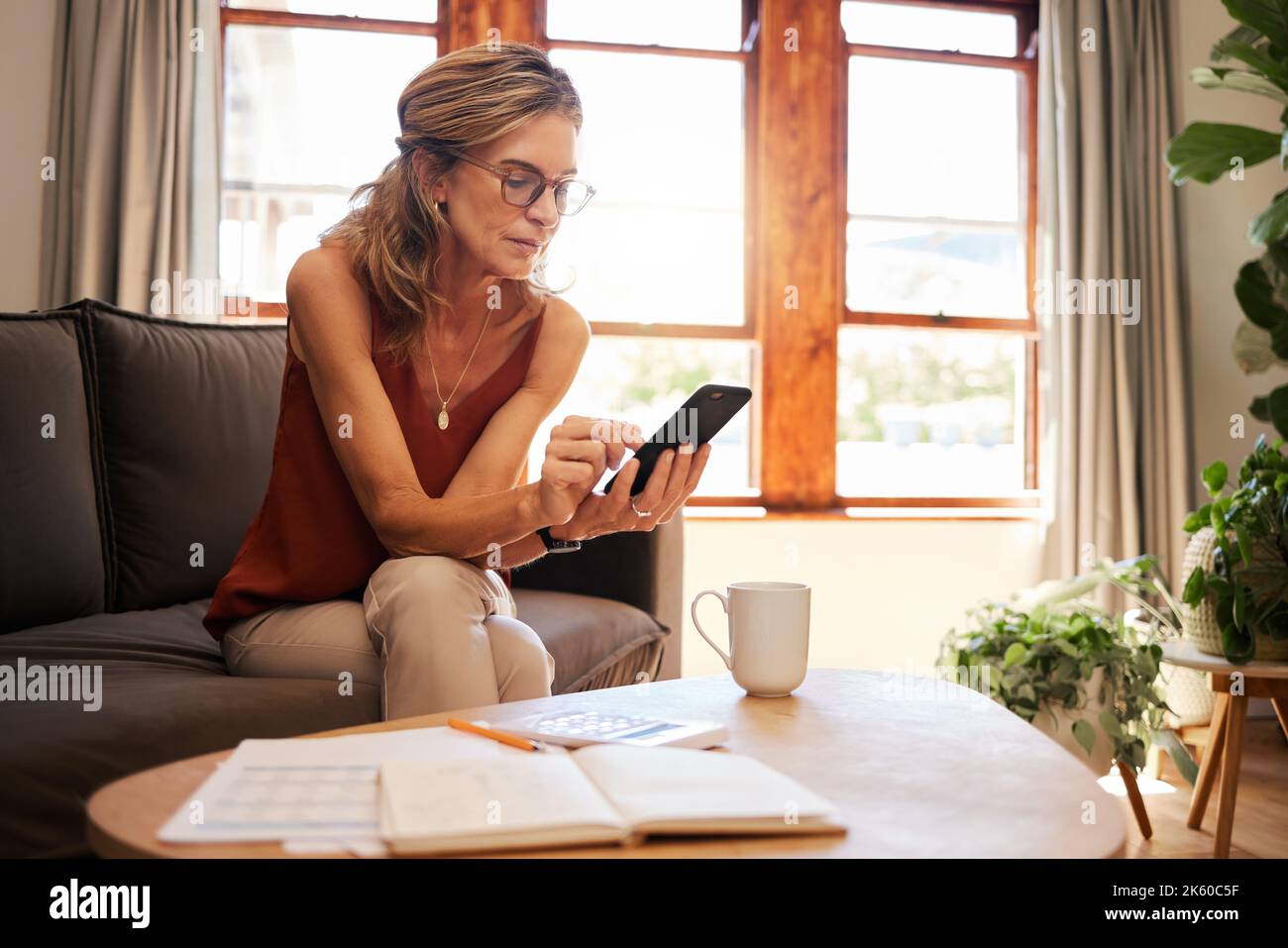 E-Mail, Buchhaltung und Senioren planen Ruhestand mit Hilfe von Handy-App und Telefon auf dem Sofa. Ältere Buchhalter lesen Finanzbericht auf der Stockfoto