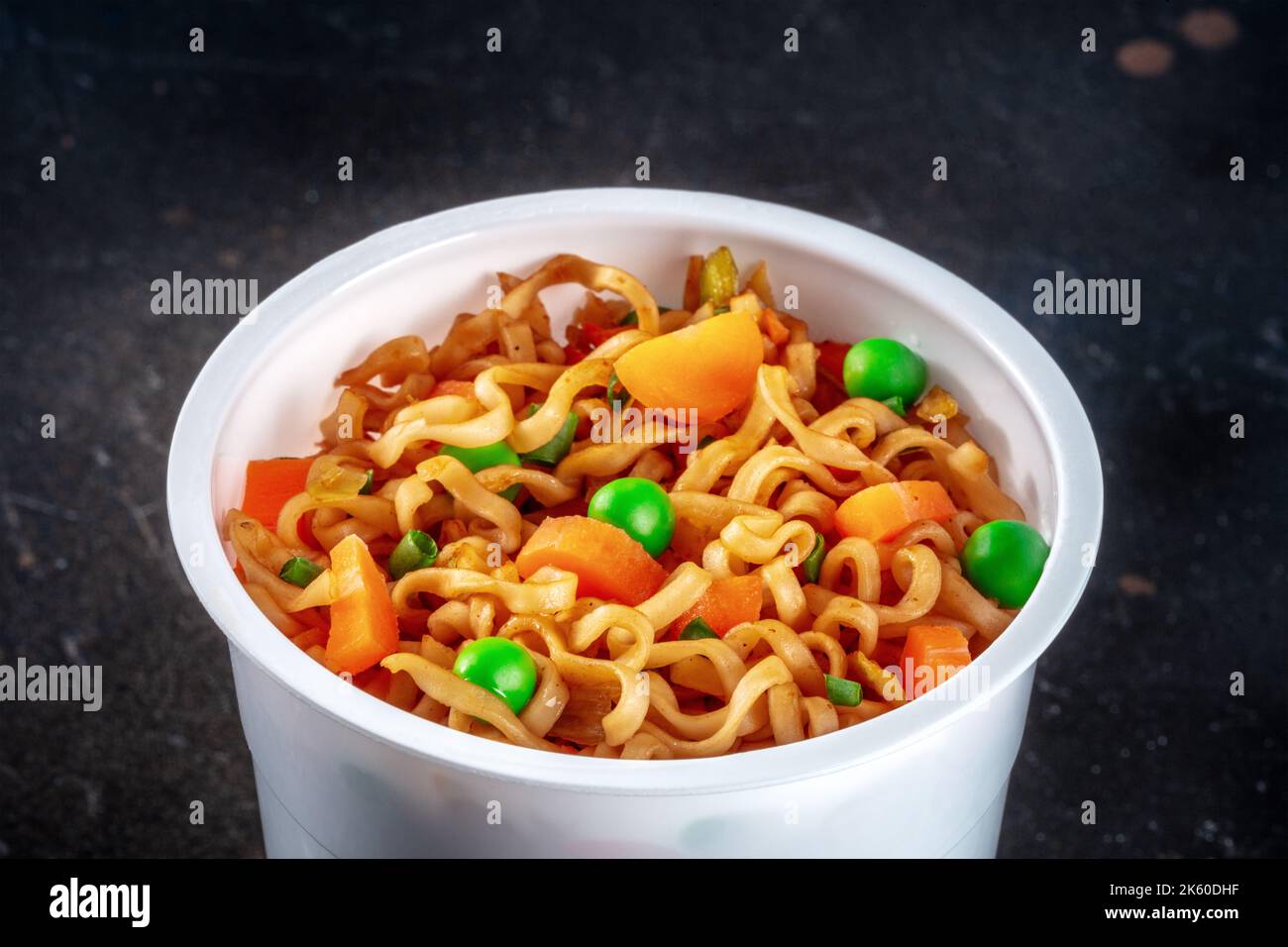 Ramen-Tasse, Instant-Soba-Nudeln in einem Plastikbecher mit Gemüse, grünen Erbsen und Karotten, Nahaufnahme Stockfoto