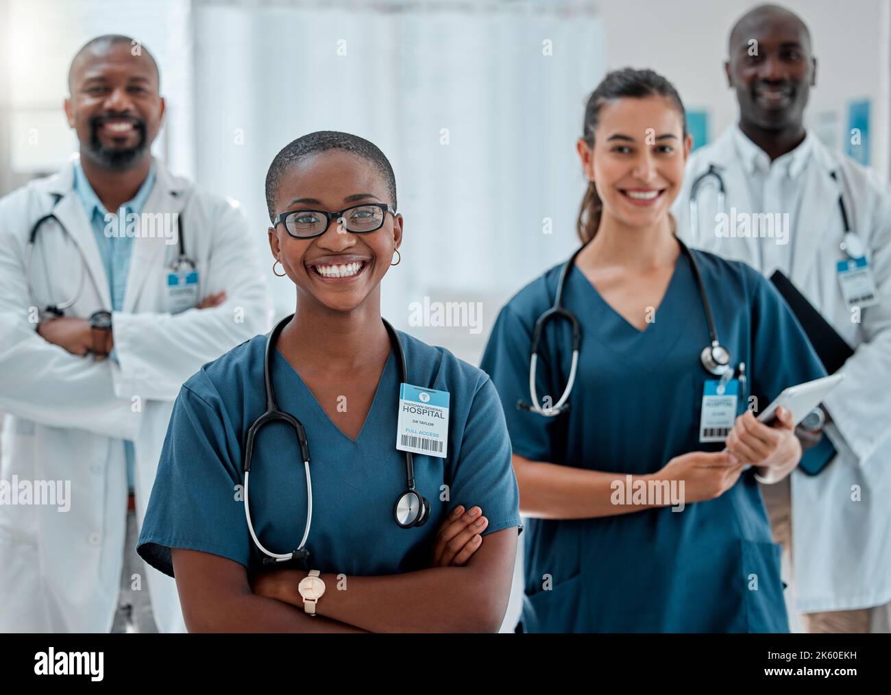 Eine Gruppe von glücklichen, vielfältigen Ärzten, die bei der Arbeit in einem Krankenhaus mit gekreuzten Armen stehen. Content-Experten für medizinische Fachkräfte, die bei der Arbeit lächeln Stockfoto