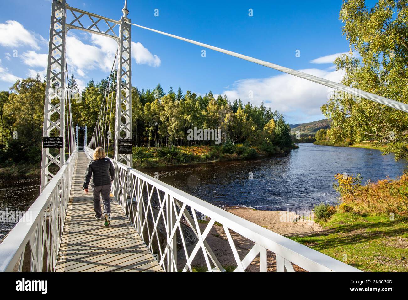 Ein Spaziergänger geht über die Hängebrücke Cambus O' May über den Fluss Dee in der Nähe von ballater in Royal Deeside, Aberdeenshire, Schottland Stockfoto