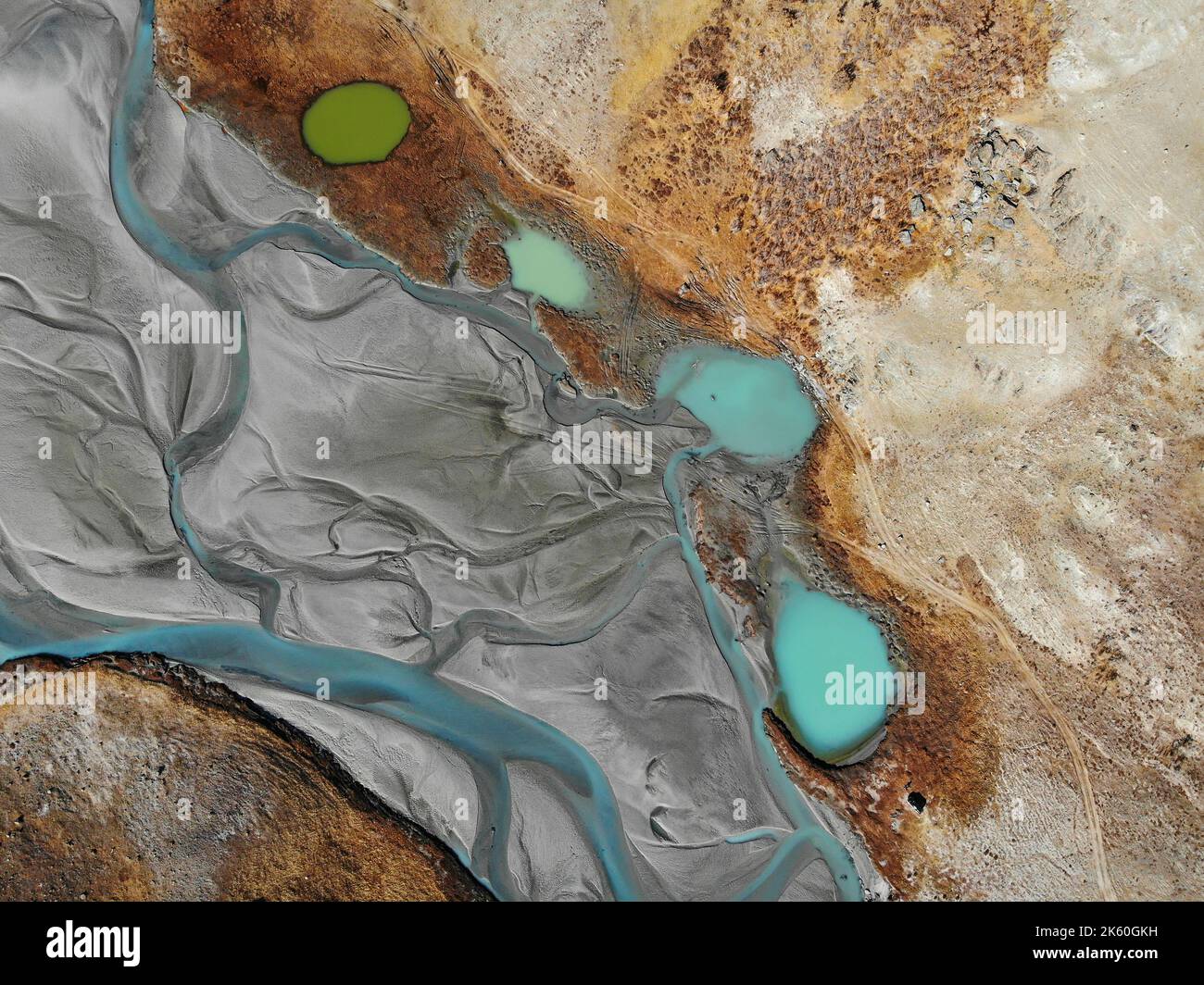 Abstrakte Herbstansicht mit Drohne auf dem Tal des schlängelnden Gebirgsflusses, See mit Wasser in verschiedenen Grün- und Türkistönen, Straße und Stockfoto