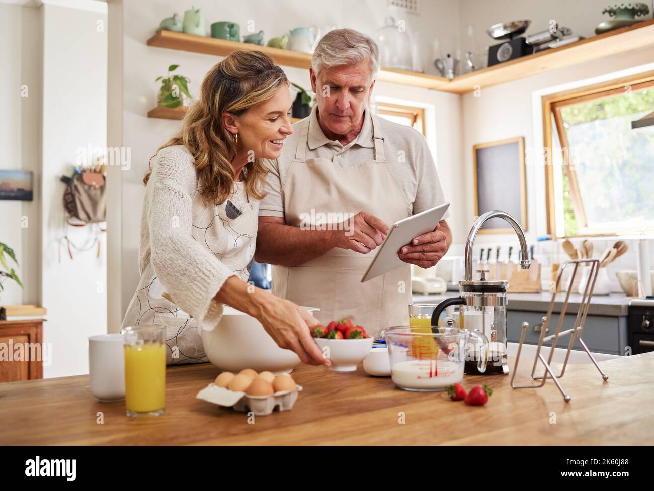 Rezept, Kochen und Senioren auf einem Tablet in der Küche mit gesunden Zutaten zu Hause. Glücklich, lächeln und ältere Männer und Frauen im Ruhestand Stockfoto