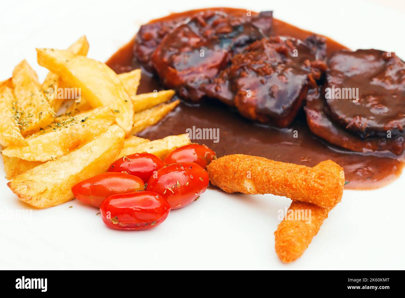 Schweineribs und Hähnchenfinger mit bbq-Sauce und ein Seite der Pommes Frites und Kirschtomaten (selektiver Fokus) Stockfoto