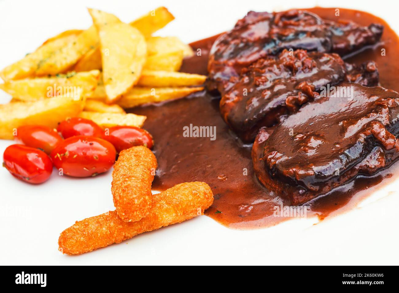 Schweineribs und Hähnchenfinger mit bbq-Sauce und ein Seite der Pommes Frites und Kirschtomaten (selektiver Fokus) Stockfoto