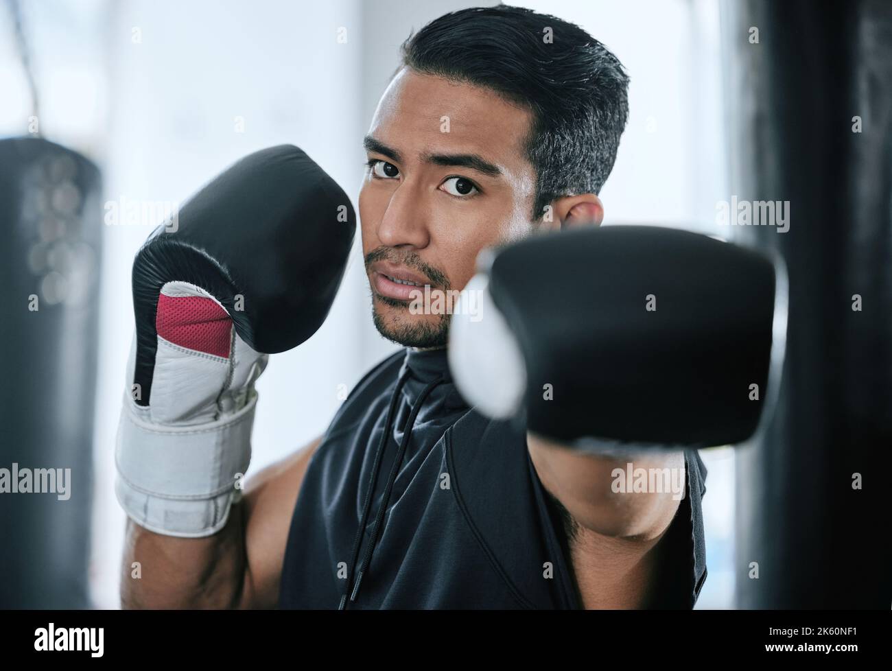 Porträt eines ernsthaften Trainers in Boxerhaltung allein im Fitnessstudio. Asian Trainer mit Boxhandschuhen bereit zu kämpfen und Punsch in der Selbstverteidigung während des Fitnessclubs Stockfoto