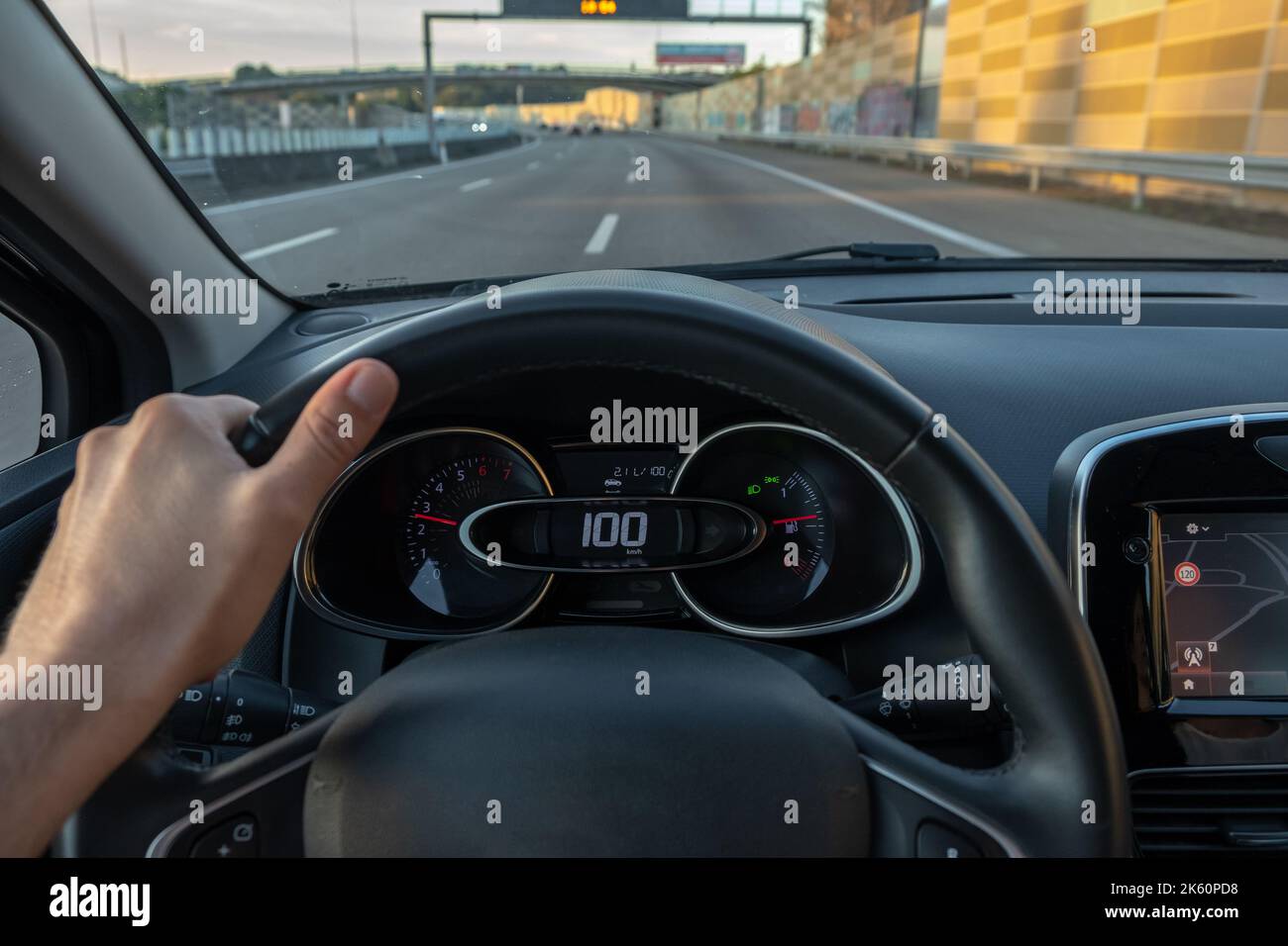 Fahreransicht auf den Tachometer bei 100 km/h oder 100 mph und unscharfe Fahrbahn, Sicht vom Fahrzeuginnenraum aus auf den Fahrer-POV der Straßenlandschaft. Stockfoto