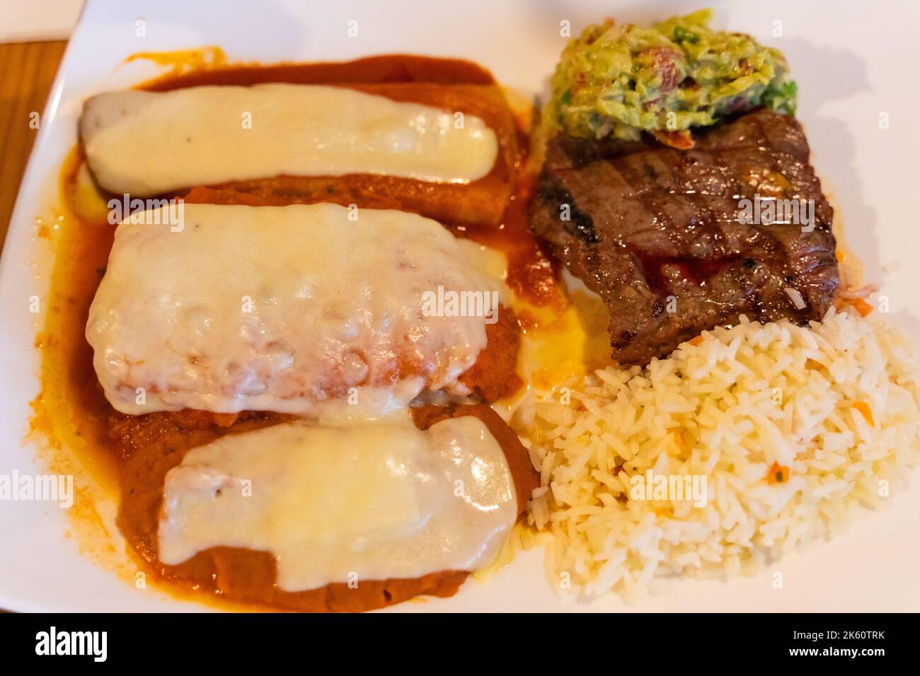 Mexikanische Enchiladas mit Reis, Rindersteak und Guacamole. Traditionelles Kombinationsmenü Stockfoto