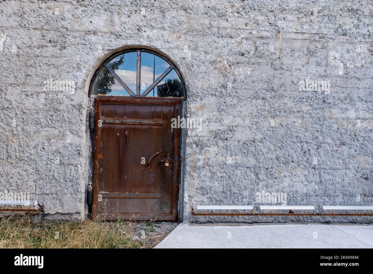 Der Eingang eines alten Industriegebäudes oder Depots mit einer alten, rostigen Metalltür. Hochwertige Fotos Stockfoto