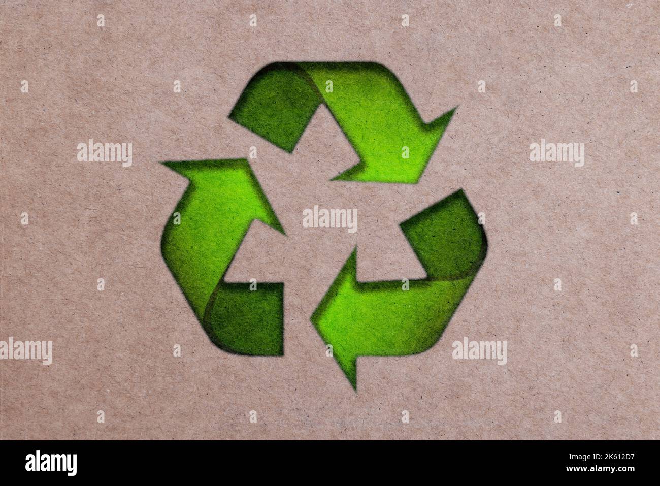 Die drei grünen Pfeile gehen in einem Dreieck, internationales Recycling-Symbol auf Brown Cardboard. Umweltfreundliches Papier oder Karton Stockfoto