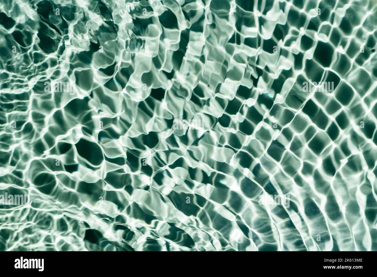 Geriffelte, transparente, frisch-blau-grüne Wassergel-Oberfläche im Schwimmbad mit Flecken, Wellen und Schatten. Gesunde Entspannung im sonnigen Sommer. Urlaub Spa Stockfoto