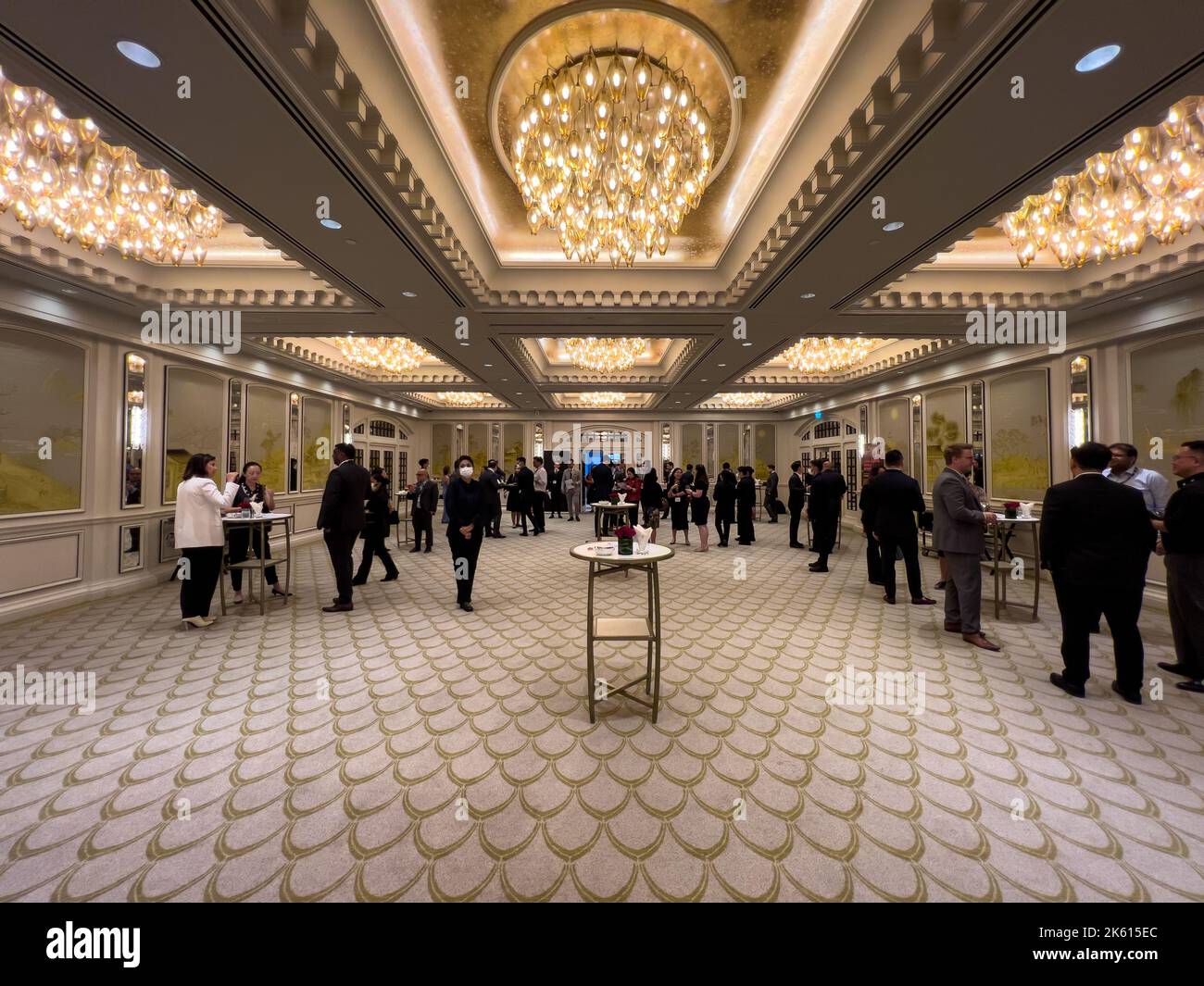 Symmetrischer Blick in einen Ballsaal, viele Geschäftsleute sind im Inneren, um während der Veranstaltung Kontakte zu knüpfen. Eine Zeit, um Netzwerke oder Beziehungen aufzubauen. Stockfoto