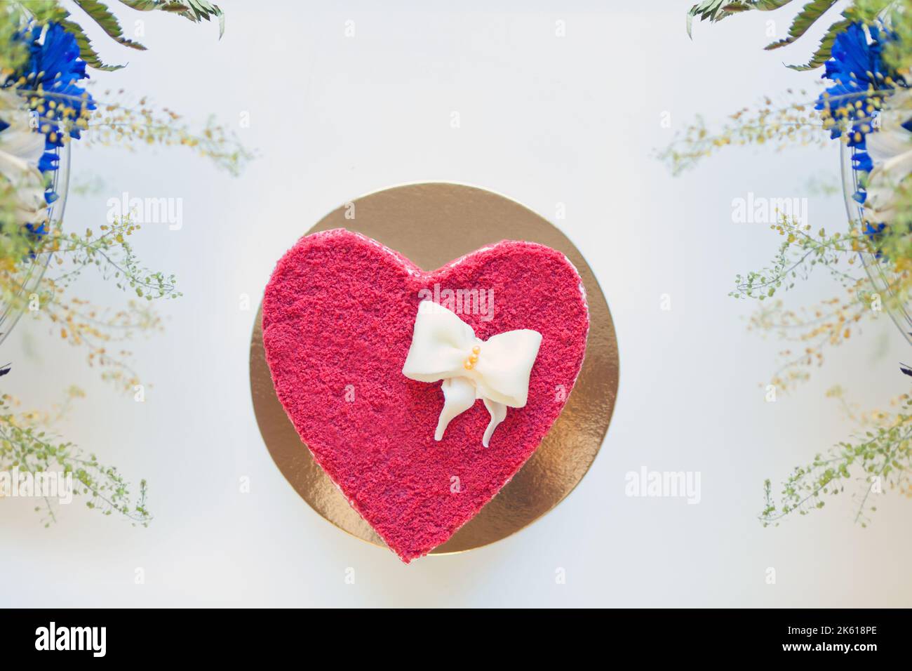 Rote herzförmige Torte mit Blumen. Torte mit Creme zum Valentinstag. Draufsicht Stockfoto