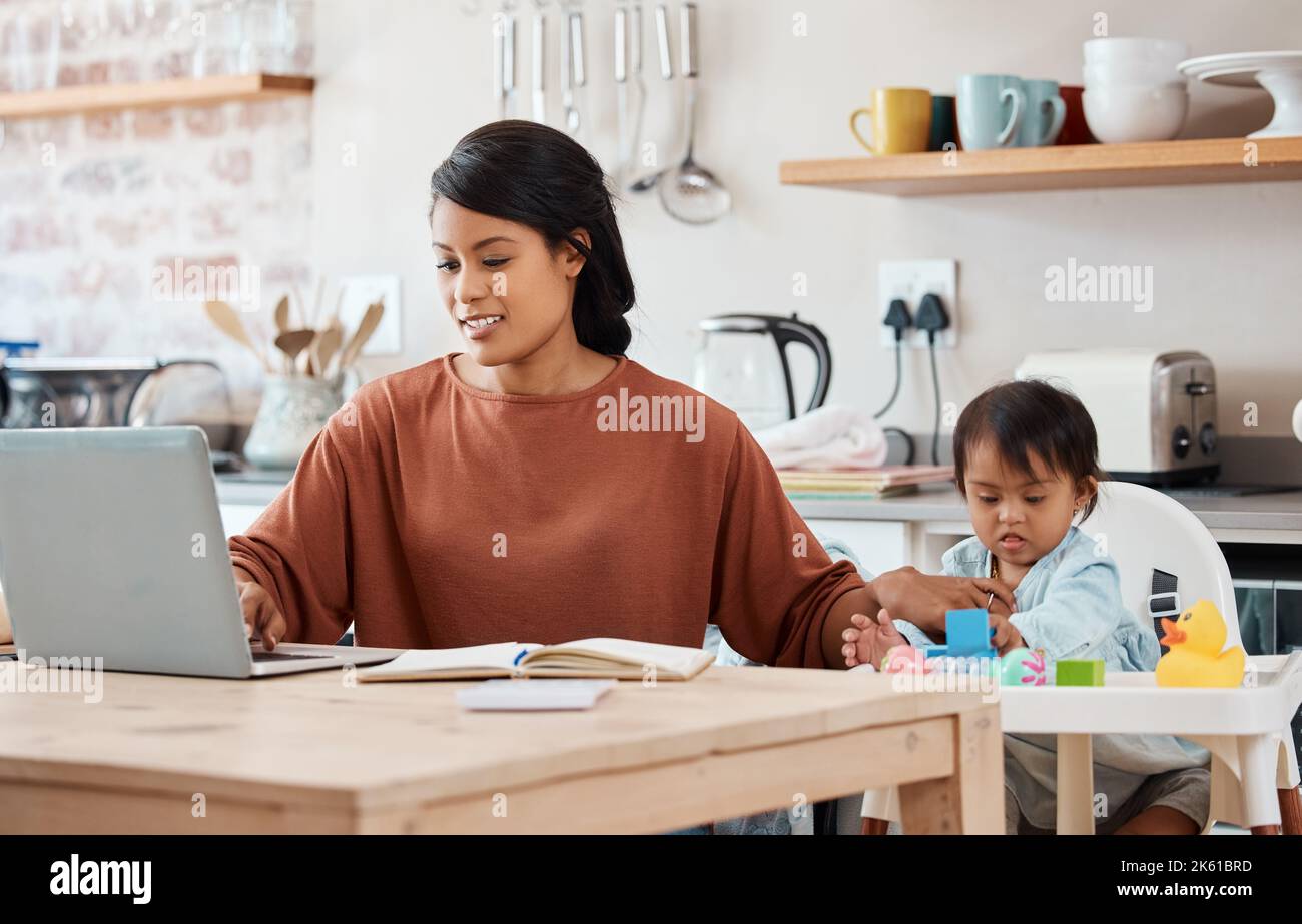 Kinder, Down-Syndrom und Familie mit einer berufstätigen Mutter und einem Kind in der Küche ihres Hauses. Kinder, Behinderung und freiberuflich mit einer Geschäftsfrau Stockfoto