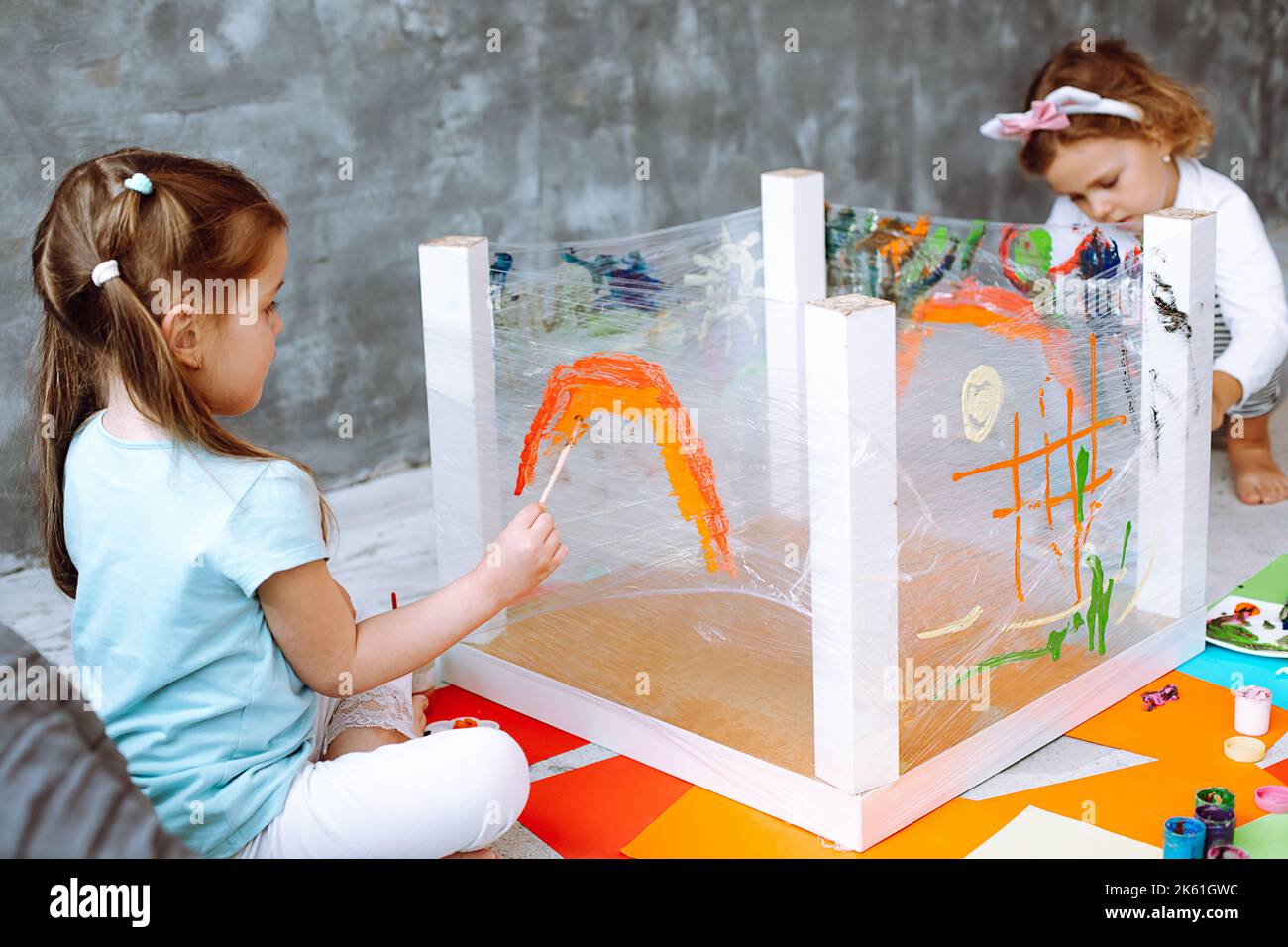 Kinder malen Regenbogen. Gruppe von Kindern Mädchen mit Lehrer lernen Farbe in der Klassenschule. Schüler zeichnen Regenbogen. Stockfoto