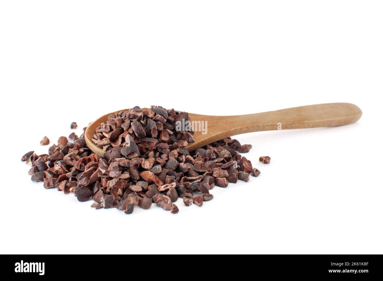 Profilansicht von Bio-Kakaospitzen roh Haufen mit natürlichen Holzlöffel auf. Isoliert auf weißem Hintergrund mit selektivem Fokus. Stockfoto