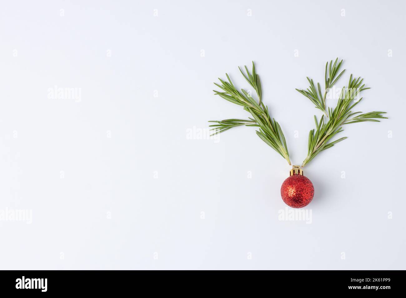 Weihnachtlich weißer minimaler Hintergrund mit Rentiergeweih aus roter Kugel und Rosmarin. Flach liegend, Kopierplatz Stockfoto