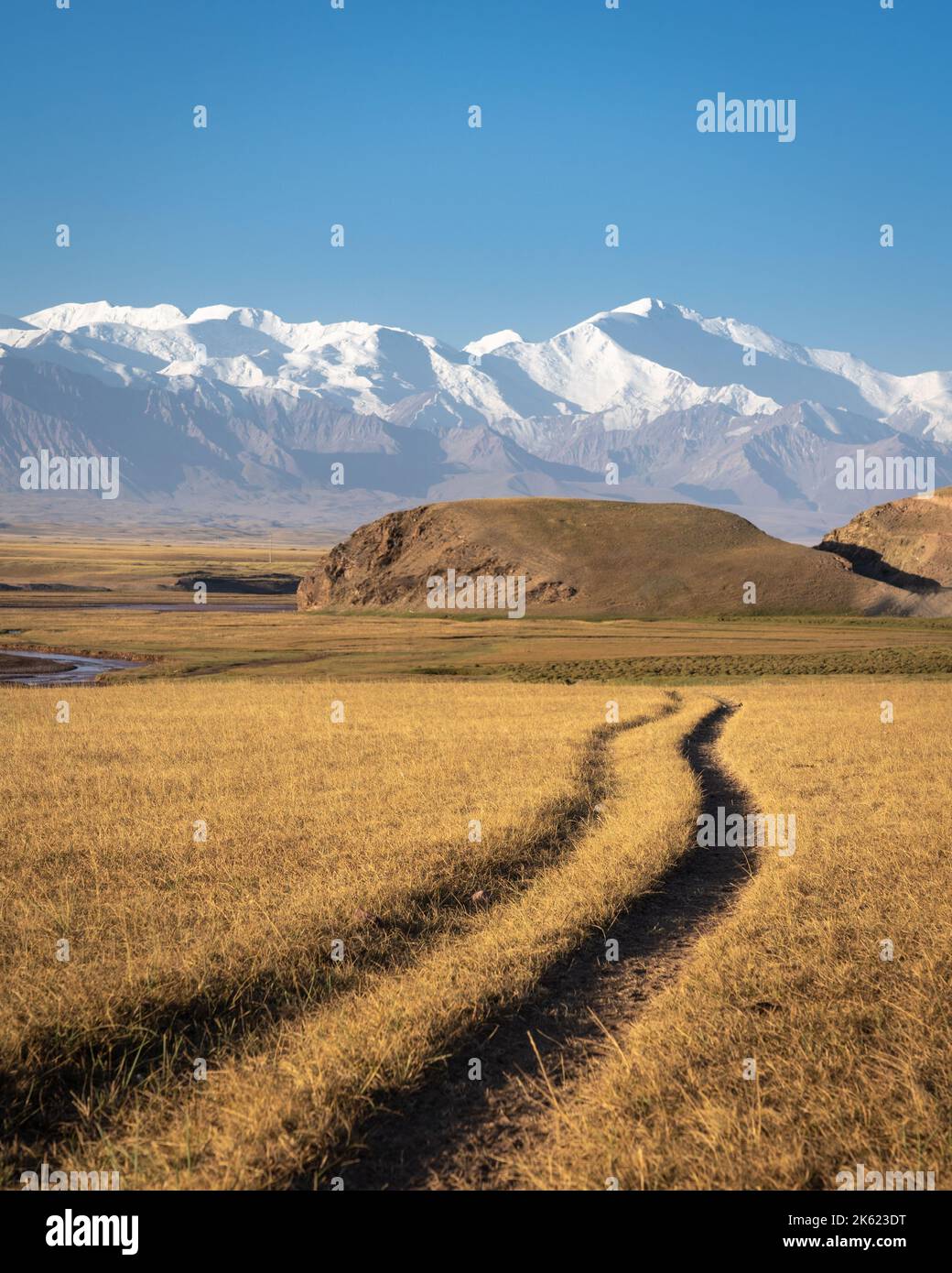 Morgens Landschaftsansicht der schneebedeckten Trans Alay Bergkette mit Lenin Peak und Spuren im Vordergrund im Süden Kirgisistans Stockfoto