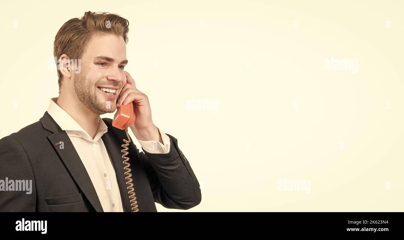 Ein glücklicher Mann-Callcenter-Betreiber ist mit einem altmodischen, altmodischen schnurgebundenen Telefon ausgestattet, das im Retro-Stil eingerichtet ist Stockfoto