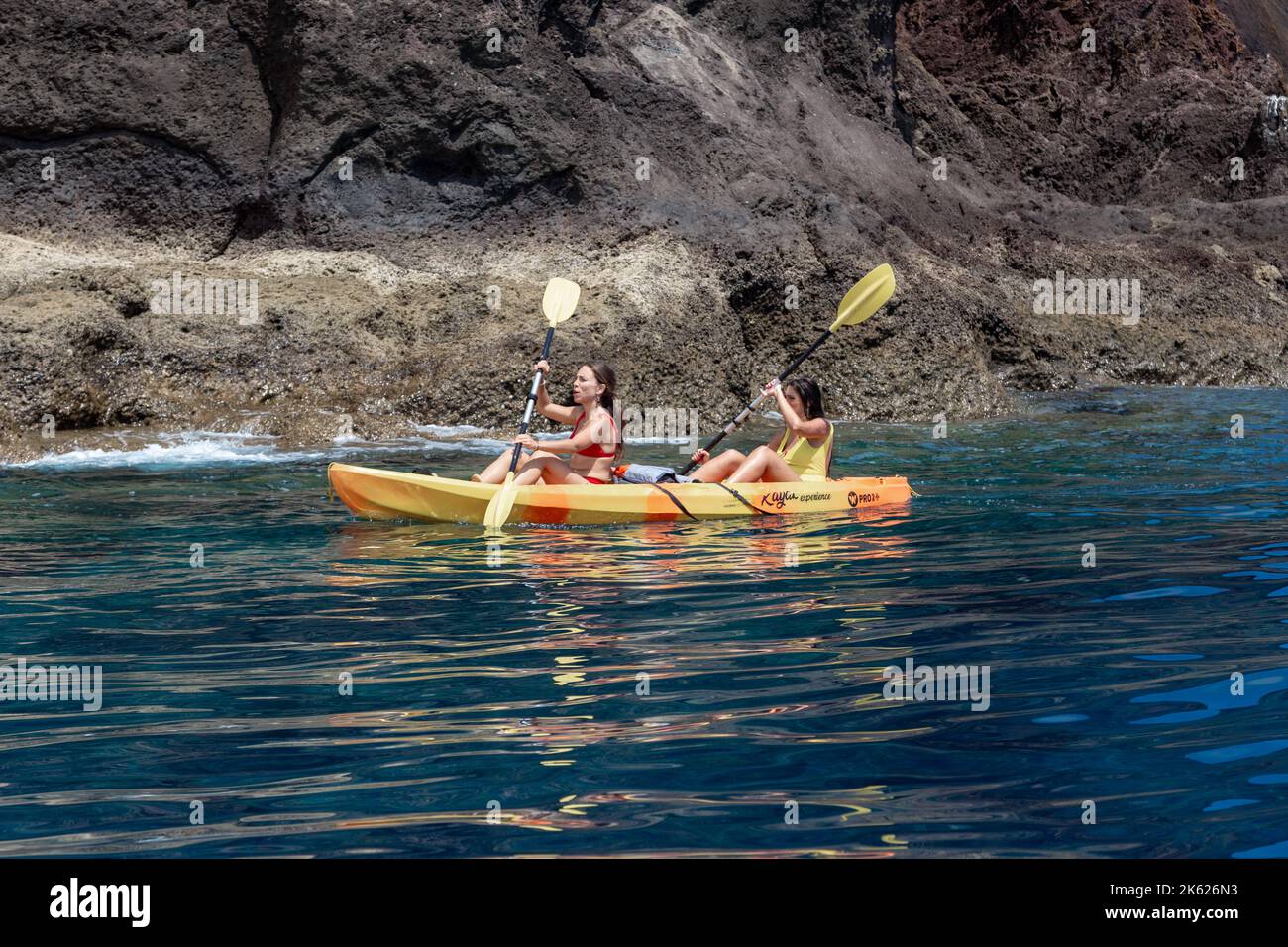 MADEIRA, PORTUGAL - 28. AUGUST 2021: Nicht identifizierte junge Frauen fahren vor den felsigen Küsten der Insel mit dem Kajak. Stockfoto MADEIRA, PORTUGAL - 28. AUGUST 2021: Nicht identifizierte junge Frauen fahren vor den felsigen Küsten der Insel mit dem Kajak. Stockfoto