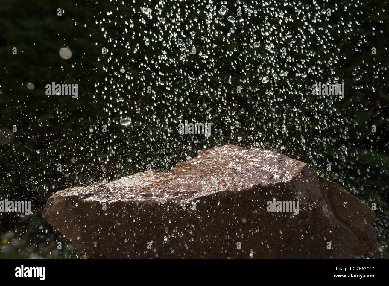 Regentropfen fallen auf einen Felsen Stockfoto