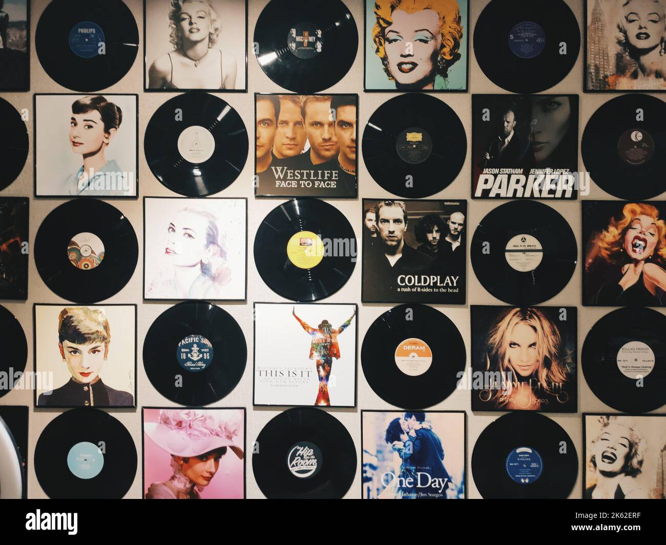 Das Album umfasst und Vinyl-Schallplatten von berühmten Sängern und Bands an der beigefarbenen Wand Stockfoto