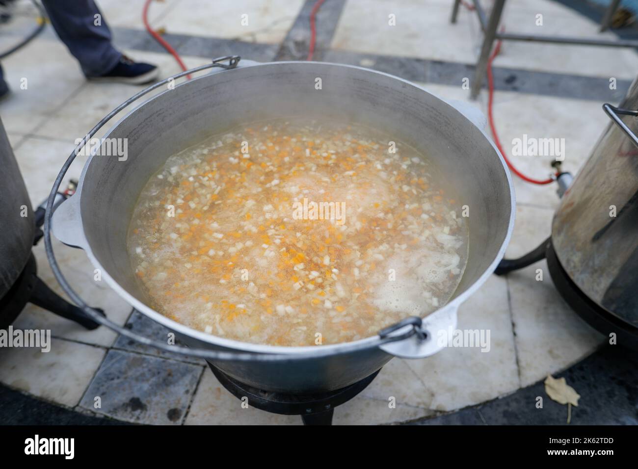 Details zur geringen Schärfentiefe (selektiver Fokus) mit einem großen Metallkessel, in dem eine traditionelle rumänische Fischsuppe (Ciorba de peste) coo ist Stockfoto