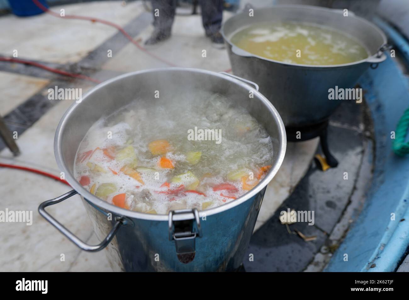 Details zur geringen Schärfentiefe (selektiver Fokus) mit einem großen Metallkessel, in dem eine traditionelle rumänische Fischsuppe (Ciorba de peste) coo ist Stockfoto