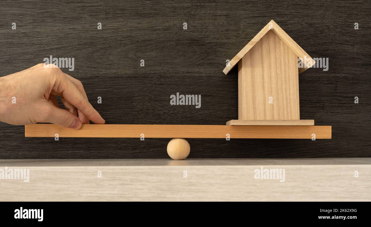 Die Hand einer Person, die das schwere Gewicht der Aufrechterhaltung eines Hauses ausbalanciert. Stockfoto