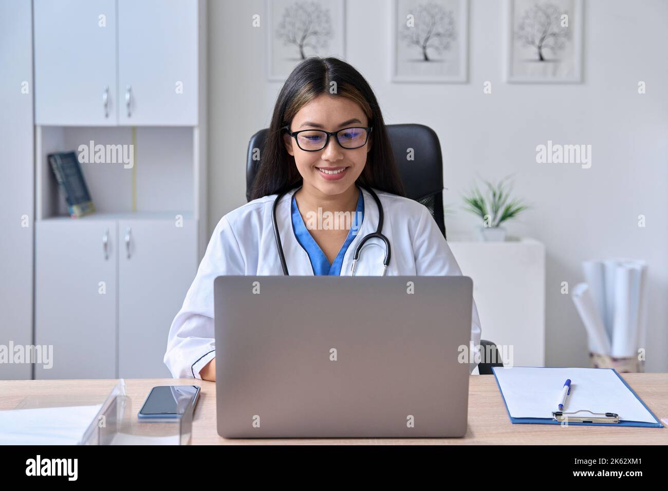 Junge asiatische weibliche Arzt Blick auf Laptop-Bildschirm hält Online-Konsultation Stockfoto